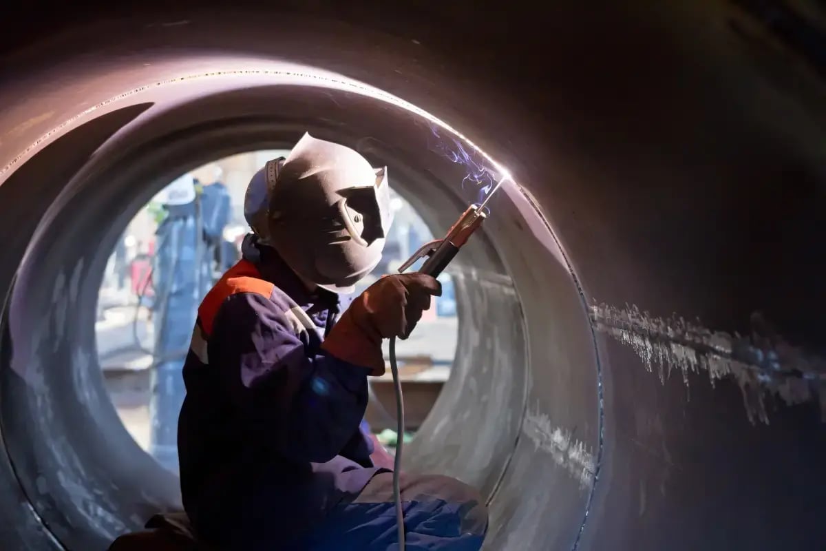 Welder with mask inside of a large cylinder structure welding