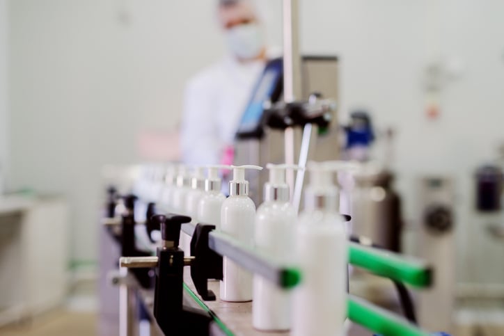 lotion bottles lined up in conveyor belt ready to be mixed